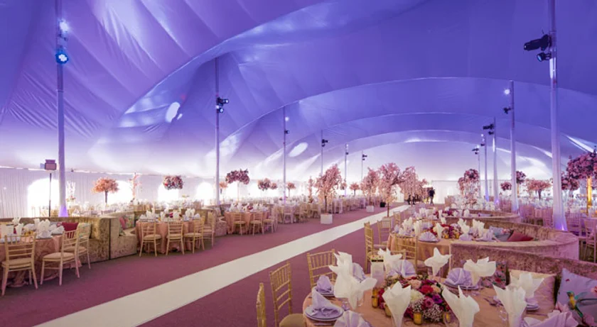 Marquee wedding reception interior with pink and purple lighting and round tables