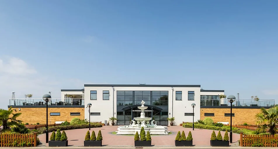 Modern white venue building exterior with fountain and landscaped grounds