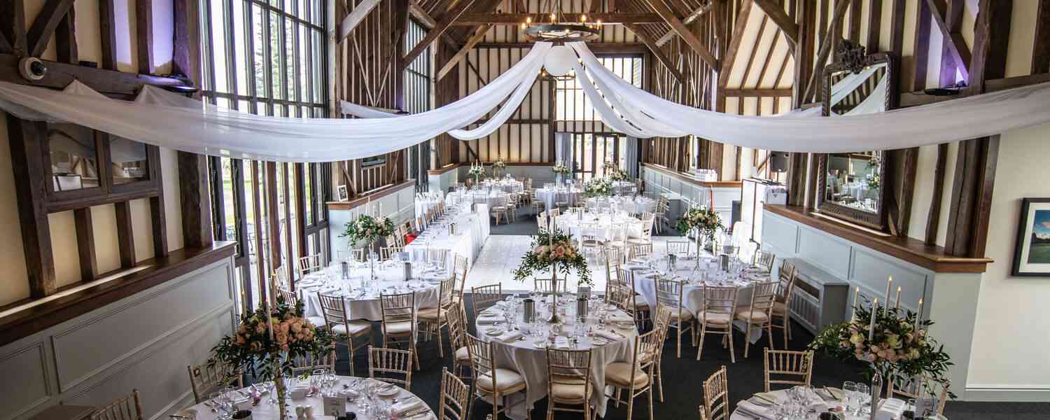 Essendon Golf club (Golf course)(Barn) 1 Timber-framed barn wedding venue set with round tables and white drapery