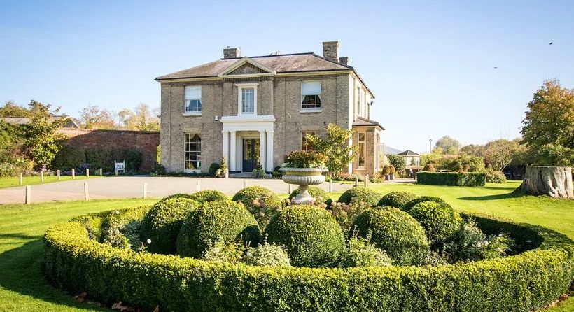 Brick wedding venue building with neatly hedged gardens