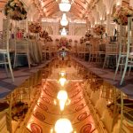 Indoor wedding aisle with a mirrored floor and hanging lights leading to the stage