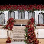 Cream and gold wedding stage with a tall floral arch and matching aisle decor