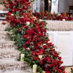 Wedding stage viewed down a red carpet aisle with rose petal decor