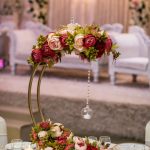 Gold hoop centrepiece with red and pink roses in front of a white sofa setting