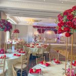 Tall red rose table centrepieces set in an elegant chandelier-lit room