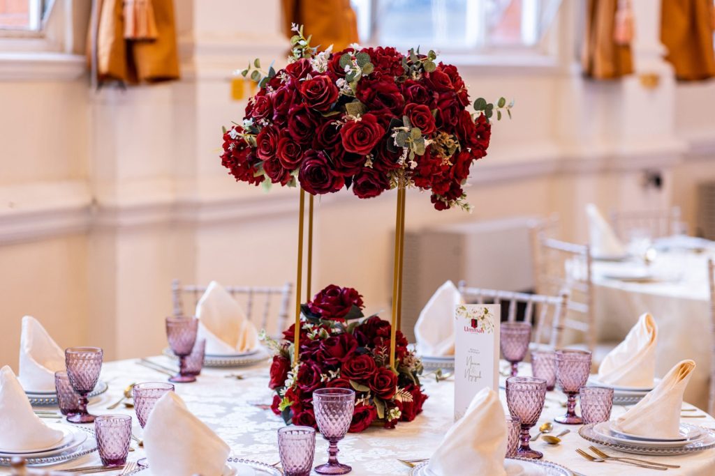 Halal Wedding Catering with a Twist: Fusion Bengali Menus for London’s Modern Couples 1 Tall red rose floral centrepiece displayed against a plain wall