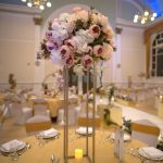 Tall white floral centrepiece on a slim stand at a wedding table