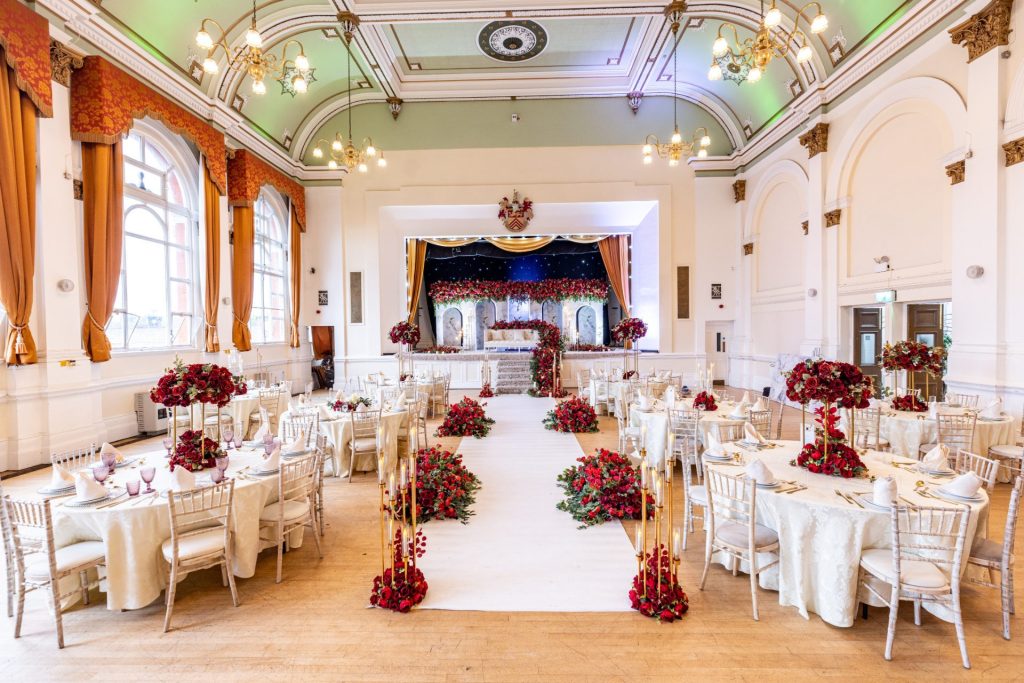 Our Guide to Asian Weddings 1 Wedding hall decorated in red and gold with an ornate stage backdrop