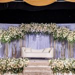 Wedding stage backdrop with gold drapes and cascading floral arrangements