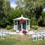 Outdoor garden gazebo set up with rows of white chairs for a wedding ceremony