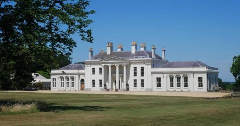 White mansion venue exterior surrounded by lawn and trees
