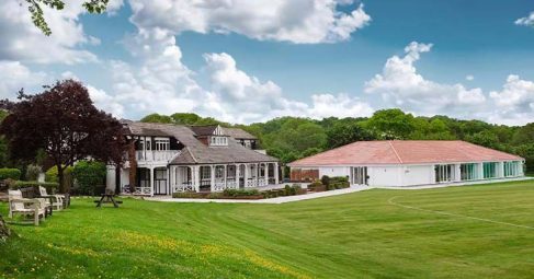 White venue building exterior with a large lawn and trees
